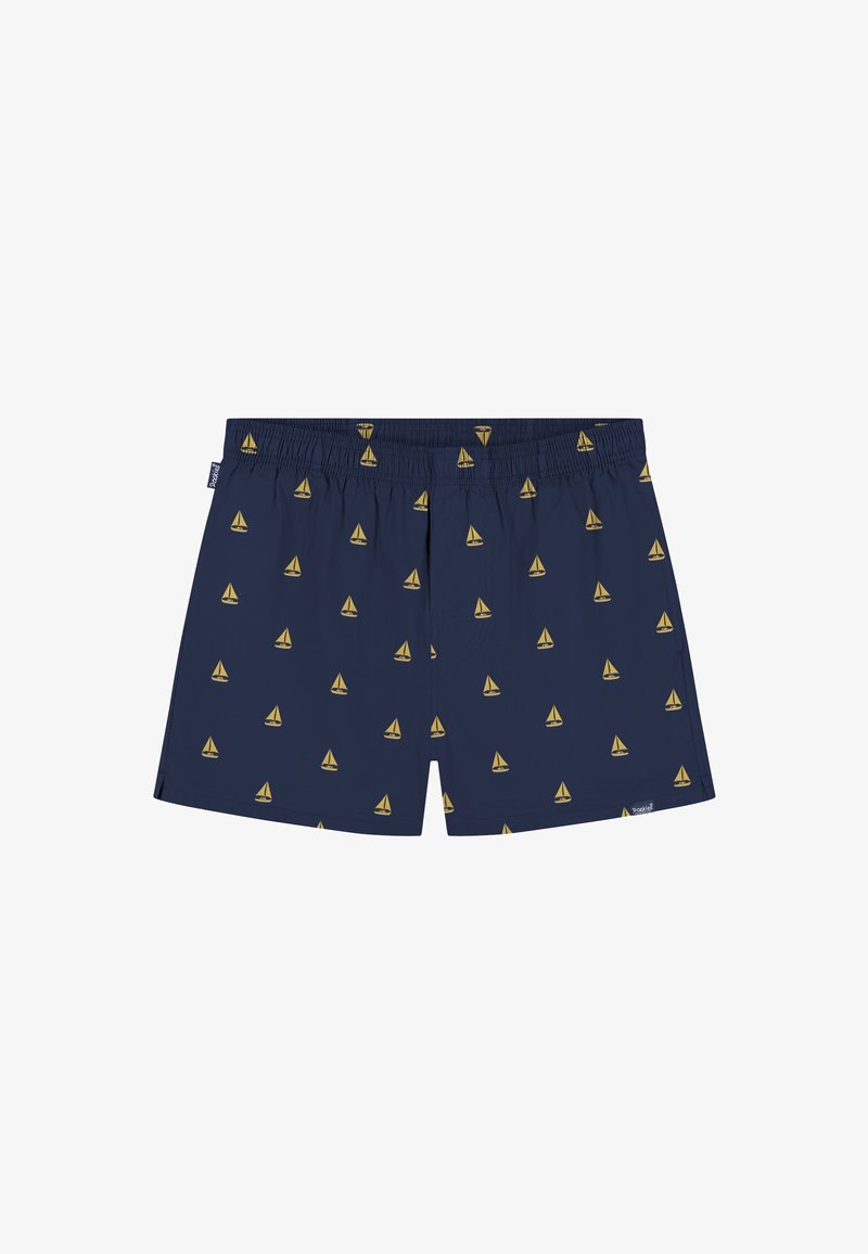 Shorts de bain pour hommes bleu marine avec motif de voiliers jaunes, taille élastique et petites étiquettes de marque sur le côté gauche et l'ourlet inférieur.