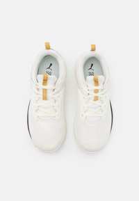 Bílé sportovní boty s vrškem z prodyšné síťoviny, žlutým akcentem na jazyku a černou podrážkou. Obsahují tradiční design na šněrování.