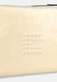 Crèmewit ritstasje van getextureerd kunstleer, met een zeshoekig reliëfpatroon aan één kant.