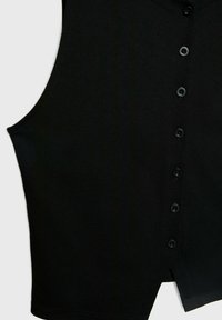 Vêtement noir sans manches avec une patte de boutonnage sur le devant et une petite fente à l'avant de l'ourlet.