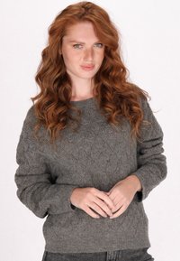 Szürke kötött pulóver gyémánt mintával, hosszú ujjakkal és kerek nyakkivágással. Puha tapintású, laza szabású, bordázott alsó szegéllyel.