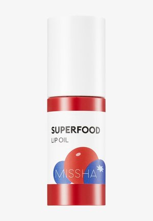 Flacon d'huile à lèvres avec bouchon blanc, base rouge, étiqueté "Superfood Lip Oil" et décoré d'illustrations de baies rouges et bleues.