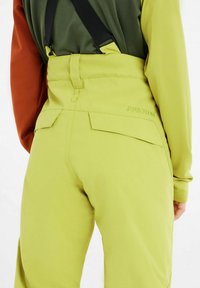 Pantaloni da sci giallo-verdi con spalline nere regolabili, caratterizzati da un design elegante, una texture liscia e un delicato dettaglio di branding sul retro.