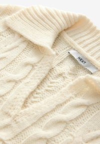 Pull en laine crème avec un motif en torsades, doté d'un col côtelé. L'étiquette indique la marque "NEXT". Fil doux et texturé.
