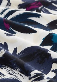 Tessuto con un motivo di audaci pennellate astratte in blu navy, teal e magenta scuro su uno sfondo crema, texture liscia.