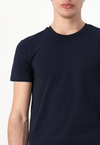 Námorně modré tričko s kulatým výstřihem vyrobené z měkké tkaniny, s krátkými rukávy a přiléhavým střihem, prezentující hladkou a jemnou texturu.