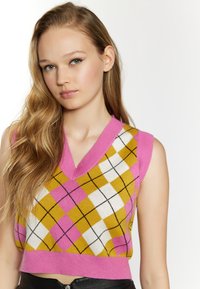 Maglione senza maniche lavorato a maglia con scollatura a V, caratterizzato da un motivo argyle rosa, giallo e bianco, dettagli neri e orlo corto. Texture morbida.
