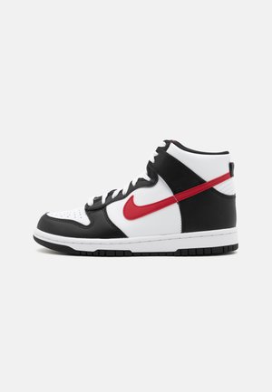 Baskets montantes avec un dessus en cuir blanc, accents noirs, logo Nike rouge, bout perforé et semelle en caoutchouc blanc. Présente un design à lacets.