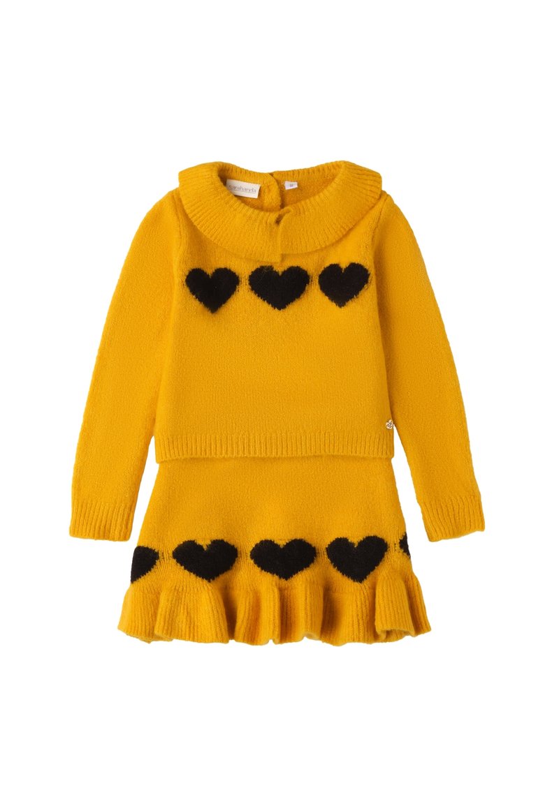 Set di maglione e gonna lavorati a maglia gialli, con collare a costine e motivi a cuore neri. La gonna presenta un orlo a volant. Texture morbida.
