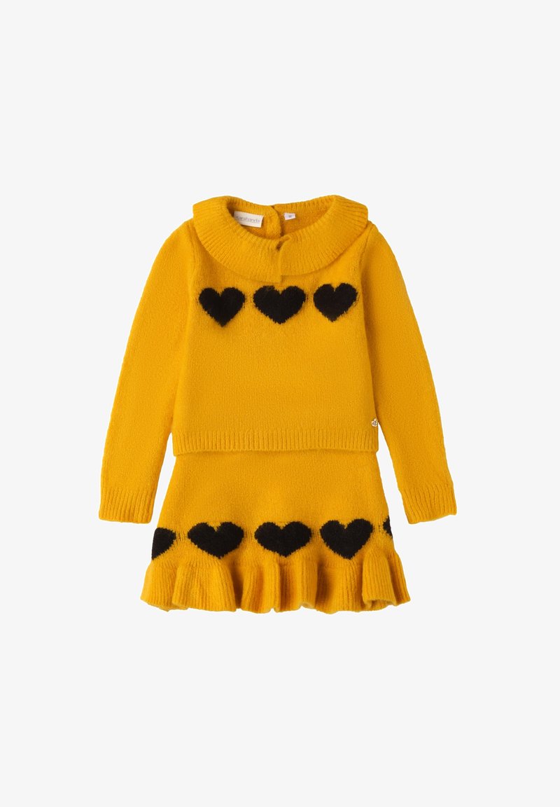 Set di maglione e gonna lavorati a maglia gialli, con collare a costine e motivi a cuore neri. La gonna presenta un orlo a volant. Texture morbida.