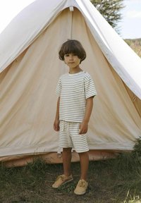 Striped short-sleeve shirt and shorts set in cream and beige. Cotton fabric. Brown shoes. Child stands in front of a beige tent. Grass visible.