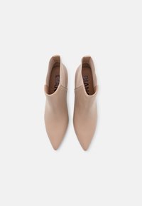 Stivaletti beige in pelle con punta affusolata, texture liscia e design senza lacci. L'interno presenta una soletta con logo.