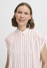 Camisa de manga corta blanca con rayas verticales rojas, que presenta un cuello abotonado y un corte holgado, hecha de tejido ligero.