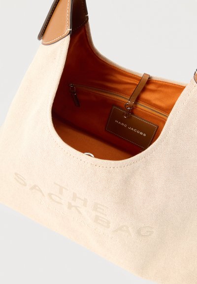 Τσάντα ώμου από καμβά με ταμπά δερμάτινη επένδυση και εσωτερικό, που διαθέτει εσωτερική τσέπη με φερμουάρ και δερμάτινη ετικέτα Marc Jacobs.
