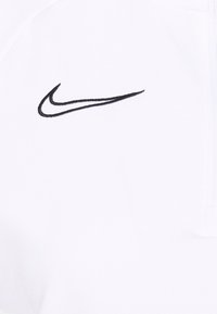 Witte hoodie met een gladde textuur, voorzien van een zwarte geborduurde Nike-logo aan de linkerkant en een ritssluiting aan de voorkant.