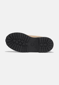 La suela de goma negra presenta profundos surcos para una mejor tracción. Parte superior de ante en color marrón con detalle del logo cerca del talón. Diseño duradero para uso exterior.