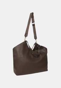 Sac en cuir texturé marron foncé avec une bandoulière large réglable et de petits accessoires en or sur fond blanc uni.
