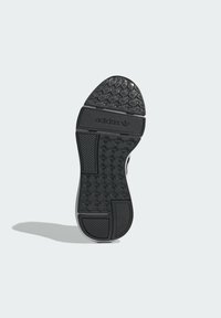 Suola in gomma nera per sneaker con motivo di presa testurizzato e branding. Presenta un tallone liscio e elementi di trazione multidirezionale.