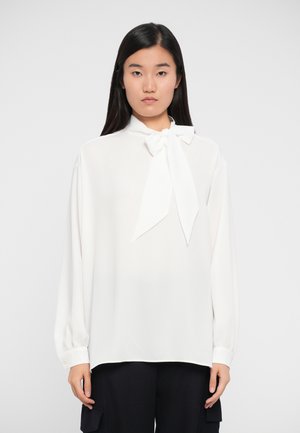 White blouse with a high neck, bow tie detail, long sleeves, and cuffs. Smooth, lightweight fabric with a loose fit.