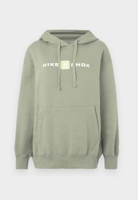 Zelená mikina s kapucňou, s vreckom kangaroo, kapucňou so sťahovacou šnúrkou a bielym logom Nike Shox na hrudi. Hladká tkanina, voľný strih, rebrované manžety.