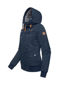 Mørkeblå jakke med en hætte foret med pels, lynlås foran og snorjusteringer. Har ribstrikkede manchetter og et logopatch på ærmet.