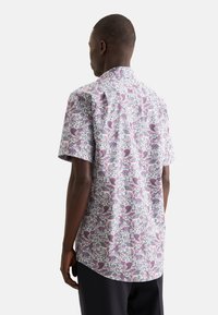 Camicia a maniche corte con un motivo paisley rosa e blu, realizzata in tessuto leggero, con un orlo leggermente curvo e un colletto tradizionale.