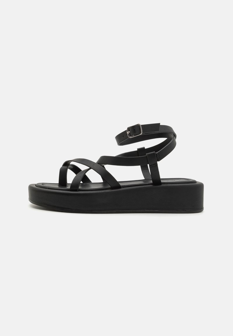 Black platform sandals with multiple thin straps and an ankle buckle. The sole is flat and slightly elevated, providing added height.