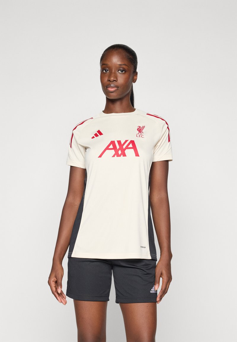 Dres Liverpool FC v krémové barvě s červenými akcenty, na kterém je klubové logo a text "AXA" vpředu. Černé šortky s logem Adidas. Hladká textura.