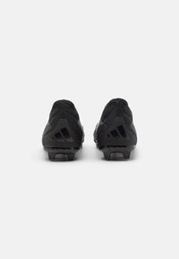 Schwarze Sportschuhe mit einer strukturierten Mesh-Oberfläche, robuster Fersenstruktur und multidirektionaler, genoppter Außensohle für Traktion.