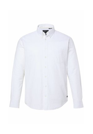 Valkoinen pitkähihaisen napillisen paidan teksturoidulla kankaalla, jossa on yksi rintatasku ja pyöristetty helma. Paidassa on klassinen kaulus ja napit hihansuissa.