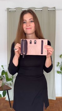 Carteira cor-de-rosa com um compartimento com fecho de correr em roxo escuro, duas correias de fixação, um bolso deslizante e detalhes em dourado. Material texturizado.