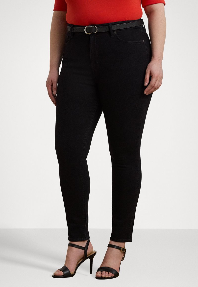 Sorte slanke jeans laget av denim, med middels høyde på livet og belte. Båret med svarte hælsandaler som fremhever en strømlinjeformet silhuett.