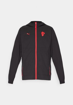 Schwarze Jacke mit rotem Reißverschluss, Kapuze und Akzenten. Verfügt über ein Puma-Logo und eine Löwengrafik auf der Brust. Leichtes Material mit elastischen Bündchen.