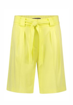Short jaune taille haute avec une ceinture en tissu nouée en nœud devant et des plis sous la taille.