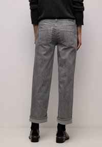 Grå jeans med slangeskindsprint og afslappet pasform, med op rullede manchetter og to baglommer. Stoffets tekstur minder om slangeskind.