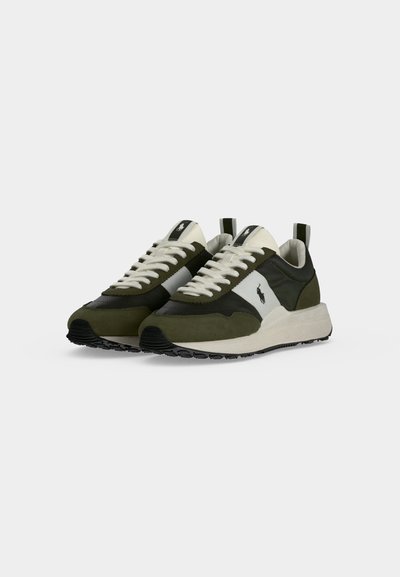 Ζεύγος πράσινων και λευκών sneakers χαμηλού ύψους με λευκά κορδόνια και μαύρο λογότυπο στα πλάγια και στη γλώσσα, εμφανισμένα σε απλό ανοιχτό φόντο.