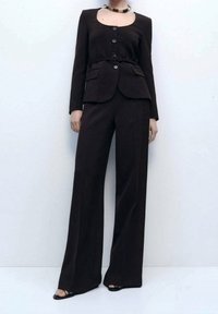 Dunkelbrauner, maßgeschneiderter Anzug mit einem taillierten Sakko mit rundem Ausschnitt, vier Knöpfen und passenden weiten Hosenbeinen. Glatte Textur, minimalistisches Design.