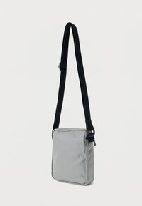 Γκρι τσάντα ώμου από ύφασμα, με απλό τετράγωνο σχέδιο, μαύρο ρυθμιζόμενο λουράκι και φερμουάρ στο πάνω μέρος.