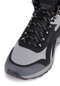 Czarno-szare buty trekkingowe z fakturowaną cholewką, wyściełanym kołnierzem i odblaskowymi sznurowadłami. Wzmocniony czubek oraz fakturowana podeszwa dla lepszej przyczepności.
