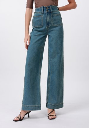 Hoch taillierte weit geschnittene Jeans aus angeschliffenem blauen Denim, mit einem Knopfverschluss vorne und zwei vorderen Taschen mit sichtbaren Nähten.