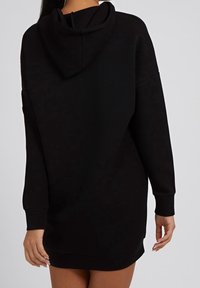 Černé mikinové šaty s kapucí, dlouhými rukávy, volným střihem a žebrovanými manžetami, s jemnou texturou a délkou do poloviny stehna.