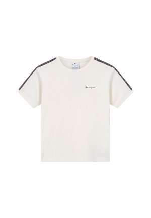 Camiseta de manga corta color crema hecha de algodón. Presenta detalles oscuros con patrón en los hombros y un pequeño logo negro en el pecho. Cuello redondo.