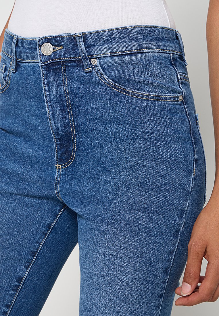 Hochgeschnittene blaue Jeans mit glatter Textur, klassischem Fünf-Taschen-Design und goldenen Nähten.