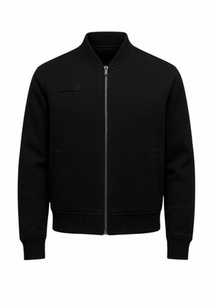 Giacca nera con zip in tessuto strutturato, colletto alto, due tasche laterali e etichetta con logo sul petto.