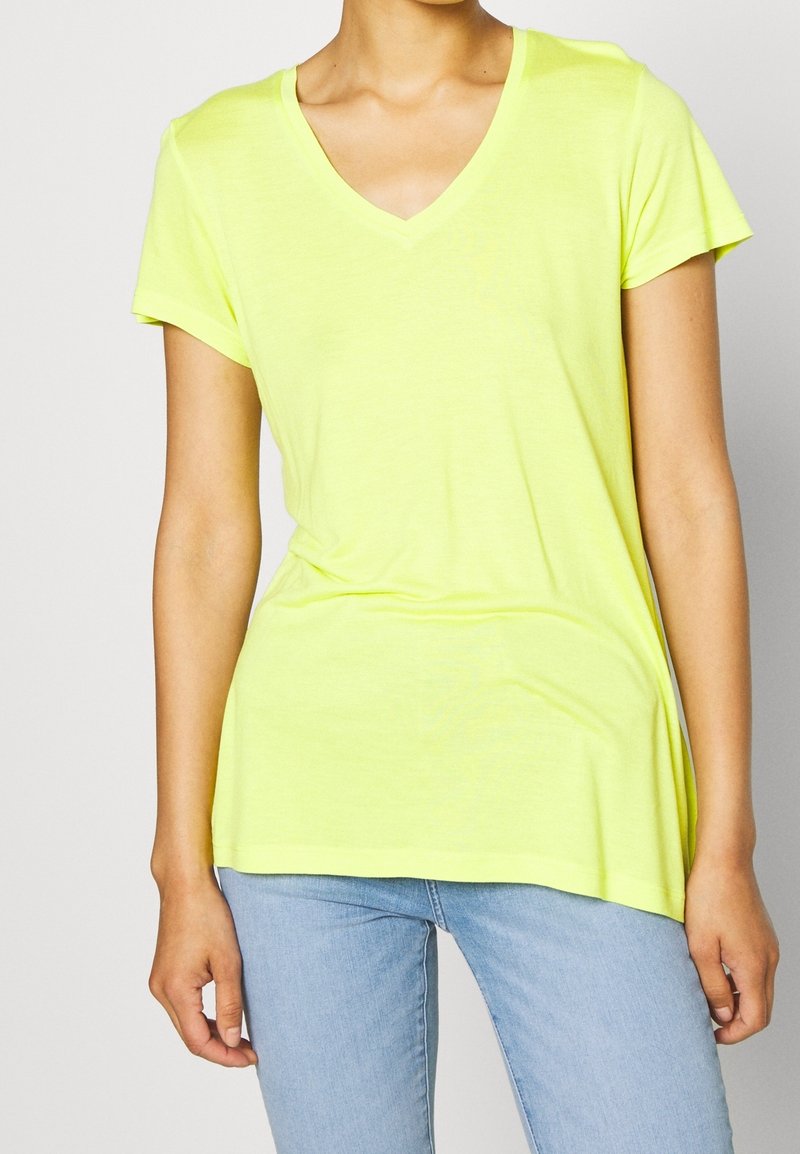 T-shirt giallo neon a V con maniche corte, realizzato in tessuto morbido. Presenta una vestibilità rilassata, un retro leggermente più lungo e una texture liscia.