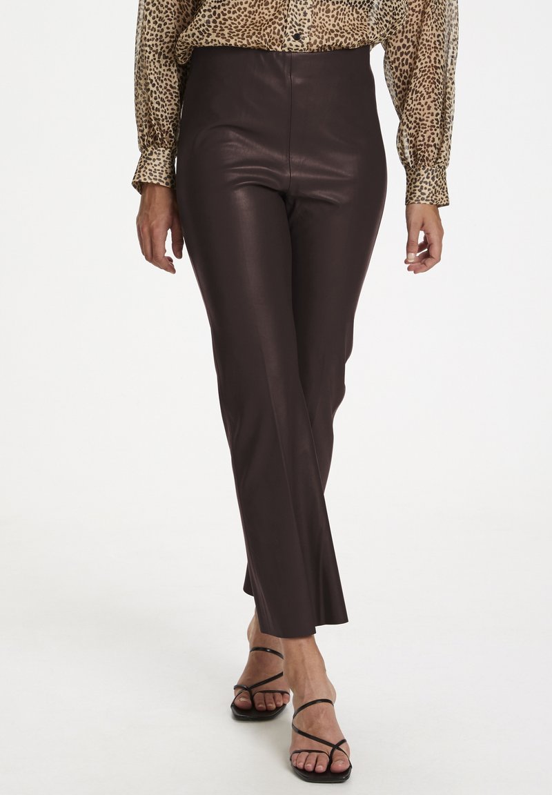 Bruna imitation läderbyxor med en åtsittande design, utsvängda vid fållen. Tillsammans med en blus med leopardtryck och svarta sandaler med remmar.