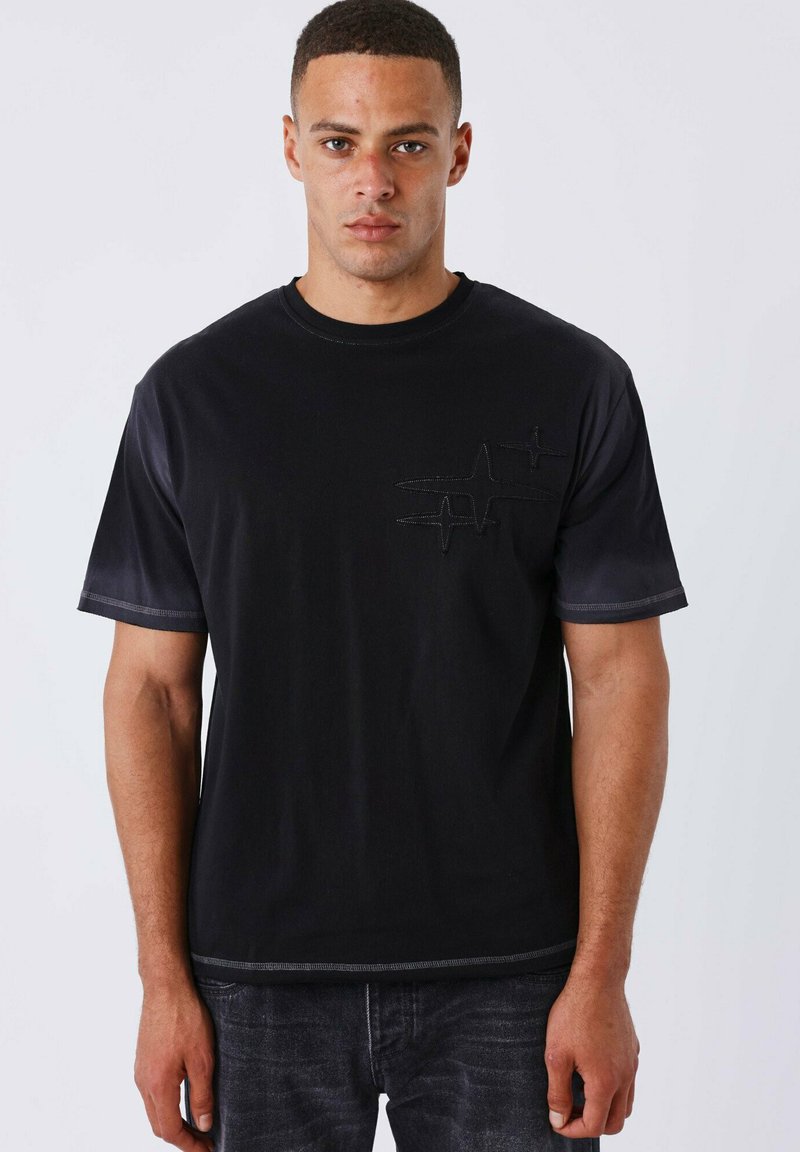Camiseta de algodón negra con un diseño texturizado de latido en el pecho, cuello redondo y mangas cortas, con detalles de costura en contraste.