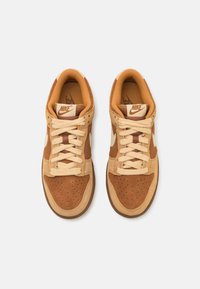 Nike tenisice imaju gornji deo od smešnog velura u boji taupe, bež kožne detalje, okrugle vezice i perforacije na prstima za prozračnost.