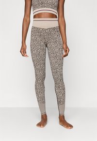 Λάτεξ σε μπεζ και καφέ στικτή παλέτα, με ψηλή μέση και αντίθετη ραβδωτή υφή και ομοιόμορφα χρωματισμένα στοιχεία.