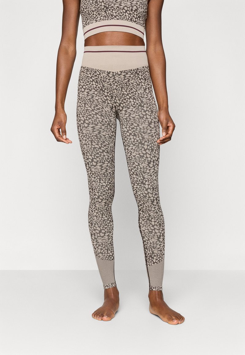 Λάτεξ σε μπεζ και καφέ στικτή παλέτα, με ψηλή μέση και αντίθετη ραβδωτή υφή και ομοιόμορφα χρωματισμένα στοιχεία.